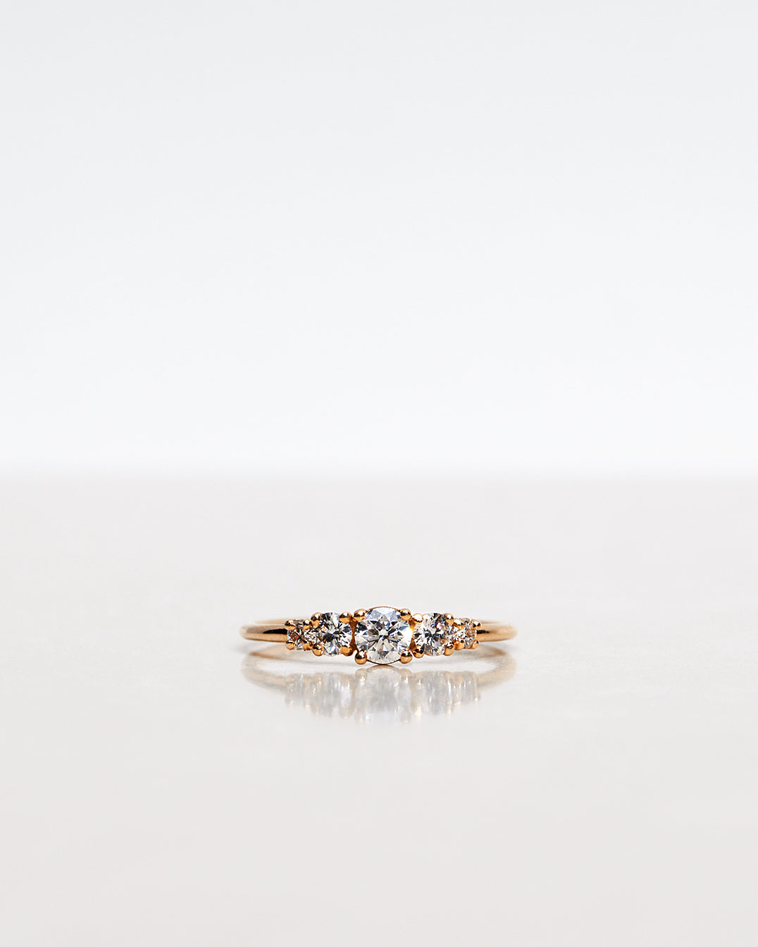 Mumbaistockholm Fine Jewelry Ring: Elise Ring in 18K yellow gold with five white, conflict-free diamonds. The center diamond is 0.25 CT, and on each side are two 0.11 CT diamonds, and two 0.04 CT diamonds. Pictured from the front.