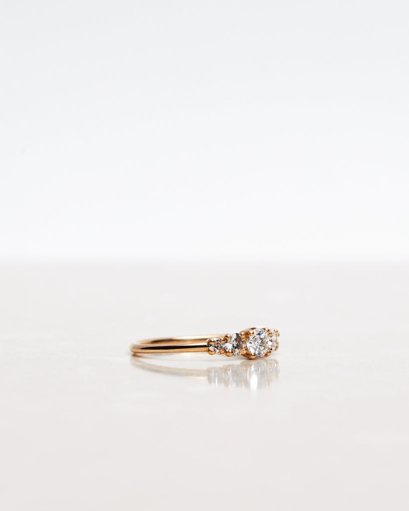 Mumbaistockholm Fine Jewelry Ring: Elise Ring in 18K yellow gold with five white, conflict-free diamonds. The center diamond is 0.25 CT, and on each side are two 0.11 CT diamonds, and two 0.04 CT diamonds. Pictured from the side.